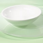 Closeup view of white bowl on a service plate — Stock Photo