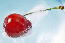 Fresh cherry floating in ice water — Stock Photo