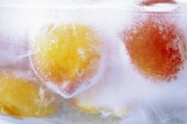 Peaches in block of ice — Stock Photo
