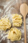 Homemade ribbon pasta and wooden spoon — Stock Photo