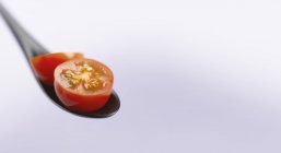 Tomate de coquetel vermelho em colher preta — Fotografia de Stock