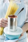 Mulher segurando espaguete e estanho de tomates — Fotografia de Stock