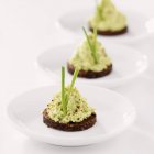 Crema di avocado su pumpernickel su piastre bianche — Foto stock