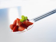 Several pieces of strawberry on plastic spoon — Stock Photo