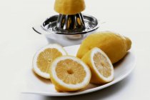 Citrons frais coupés en deux et pressoir — Photo de stock