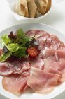 Raw ham and salami on plate — Stock Photo