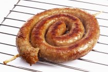 Coiled sausage on oven rack — Stock Photo