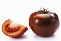 Whole tomato and wedge — Stock Photo