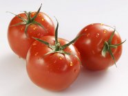 Tres tomates con gotas de agua - foto de stock