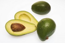 Три авокадо целые и пополам — стоковое фото