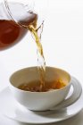 Pouring tea into a teacup — Stock Photo