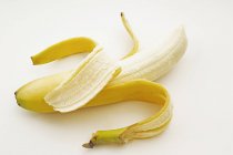 Una banana parzialmente sbucciata — Foto stock