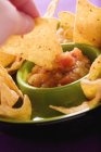 Closeup cropped view of hand dipping Tortilla chip in tomato Salsa — Stock Photo