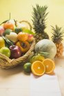 Closeup view of assortment of fresh fruits with basket on yellow background — Stock Photo