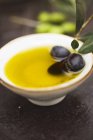 Olive oil in bowl with black olives — Stock Photo