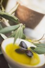 Olive oil in bowl with black olives — Stock Photo