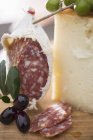 Salami with olives and Parmesan on wooden surface — Stock Photo