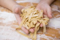 Child holding homemade ribbon pasta — Stock Photo
