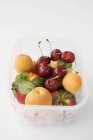 Apricots and cherries in plastic punnet — Stock Photo