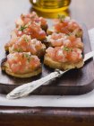 Bruschetta toasted bread with tomatoes and garlic over woden desk with knife — Stock Photo