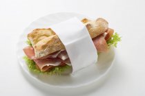 Raw ham sandwich in paper napkin — Stock Photo
