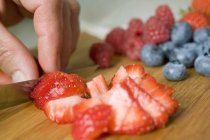 Human hands cutting strawberries — Stock Photo