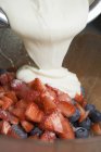 Вид крупным планом заливки сливками нарезанных ягод — стоковое фото