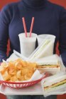 Frau hält Sandwiches, Cola und Chips auf Tablett — Stockfoto
