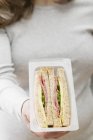 Vue recadrée d'une femme tenant un paquet de sandwichs — Photo de stock
