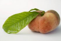 Reifer Pfirsich mit Blatt — Stockfoto