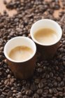 Tazas de café expreso en granos de café - foto de stock