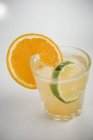 Closeup view of iced aperitif with orange and lime slices — Stock Photo