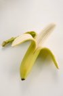 Banana gialla mezza sbucciata — Foto stock