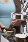 Крупним планом перегляд жінки, що кладе кавовий порошок у фільтр машини Espresso — стокове фото