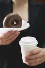 Mulher segurando donut e xícara de café — Fotografia de Stock
