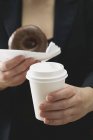 Mujer sosteniendo rosquilla y taza de café - foto de stock