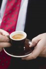 Closeup view of man in suit and tie holding cup of Espresso — Stock Photo