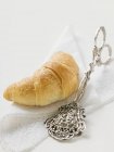 Croissant and pastry tongs — Stock Photo