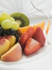 Frutas y bayas frescas en rodajas en el plato - foto de stock