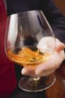Hand holding glass of cognac — Stock Photo