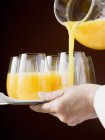 Выливание апельсинового сока в стекло — стоковое фото