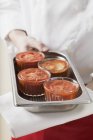 Prato de segurando Chef com quatro pequenas grades de tomate nas mãos — Fotografia de Stock