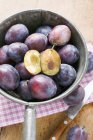 Fresh damsons with halves in metal strainer — Stock Photo