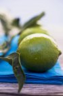 Fresh Limes on blue cloth — Stock Photo