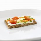 Кварк с травами и овощными палочками на цельнозерновом хлебе на белой тарелке — стоковое фото
