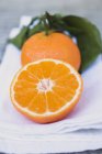 Whole clementine and half with leaves — Stock Photo