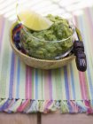 Guacamole in a small glass bowl over colored towel — Stock Photo