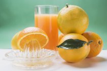 Naranjas frescas maduras y un vaso de jugo - foto de stock