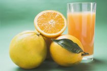 Frische reife Orangen und ein Glas Saft — Stockfoto