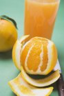 Geschälte Orangen und ein Glas Saft — Stockfoto